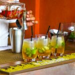 Bartender pouring rum into cocktail glasses at a vibrant bar setting.